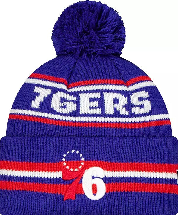 A purple knit pom-pom beanie with red and white stripes, featuring the word '76ERS' in white and the Philadelphia 76ers logo with a red ribbon and white number 6.