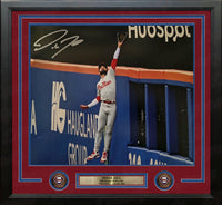 A framed 11x14 autographed baseball memorabilia print featuring Derek Hill of the Philadelphia Phillies jumping to make a catch. The piece is professionally matted with a red and blue border, set in a black frame with a custom gold nameplate and two circular team emblems.