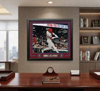 A framed Derek Hill autograph print displayed on a wall in a modern office setting. The print features a black frame, a red and blue mat, and a photo of a baseball player in a white uniform with a red helmet.