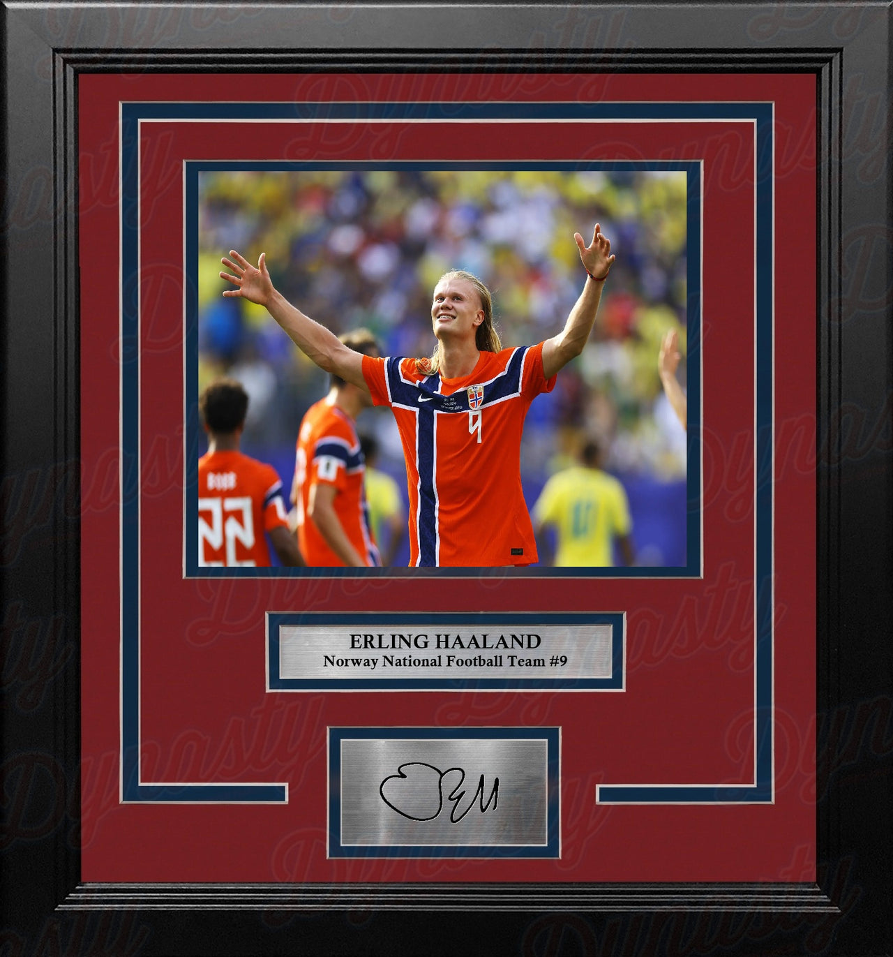 A framed sports memorabilia piece featuring a photo of Erling Haaland in an red and blue Norway national football team jersey, with a red mat, black frame, and a silver plaque at the bottom containing a replica signature.